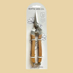 Pruning shears with wooden handles in packaging labeled 'Seattle Seed Co.' on a tan background