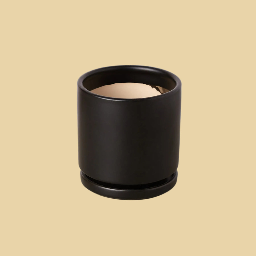 Black cylindrical container with beige interior on a plain background