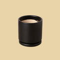 Black cylindrical container with beige interior on a plain background