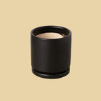 Black cylindrical container with beige interior on a plain background