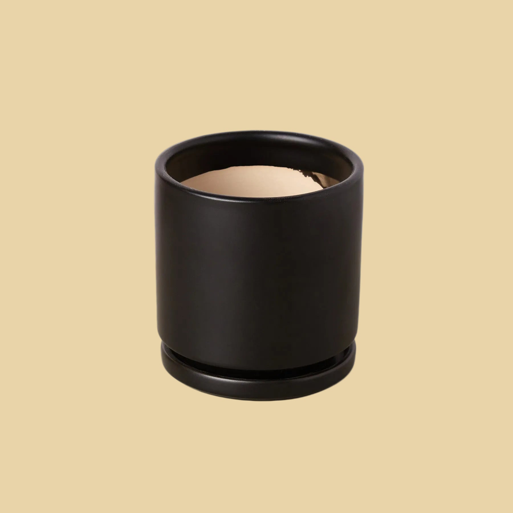 Black cylindrical container with beige interior on a plain background