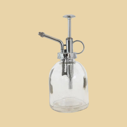 Clear glass bottle with chrome pump on a plain background